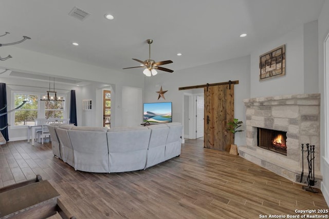 living room with a ceiling fan, wood finished floors, visible vents, recessed lighting, and a barn door