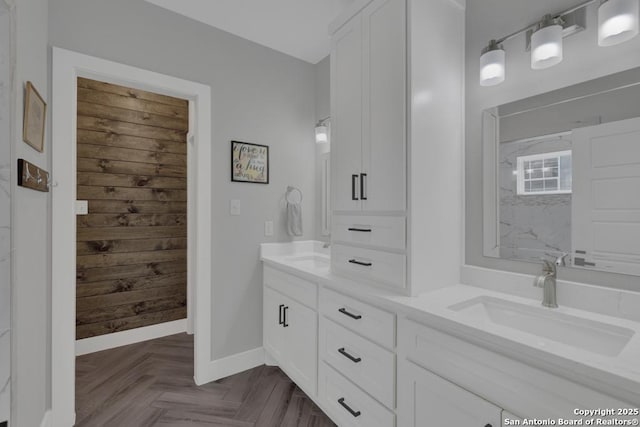 full bath with a sink, baseboards, and double vanity