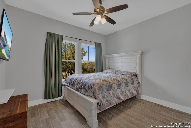 bedroom featuring a ceiling fan, baseboards, and wood tiled floor