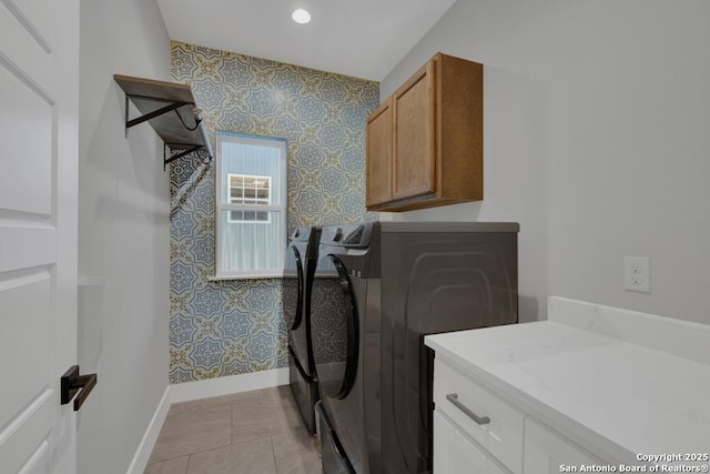 washroom with baseboards, wallpapered walls, light tile patterned flooring, cabinet space, and washer and dryer