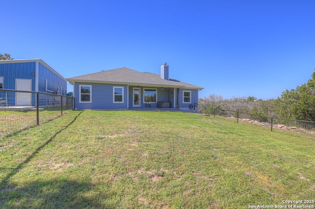 rear view of property featuring a lawn, a chimney, and fence