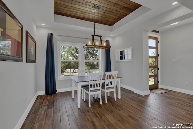 dining room with a tray ceiling, a notable chandelier, baseboards, and dark wood-style flooring