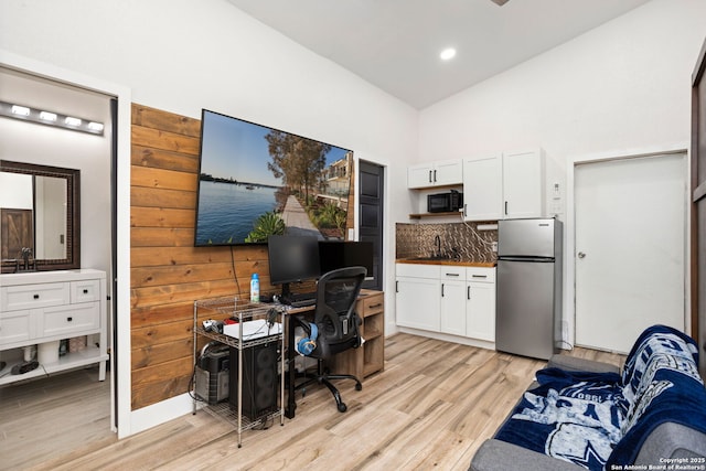 office space featuring high vaulted ceiling, recessed lighting, light wood finished floors, and a sink