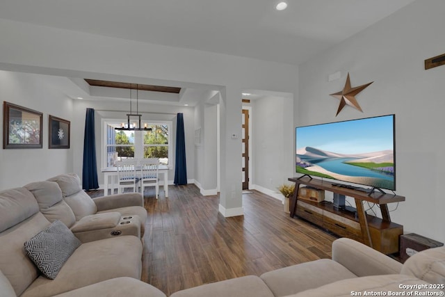 living room featuring a tray ceiling, wood finished floors, recessed lighting, baseboards, and a chandelier