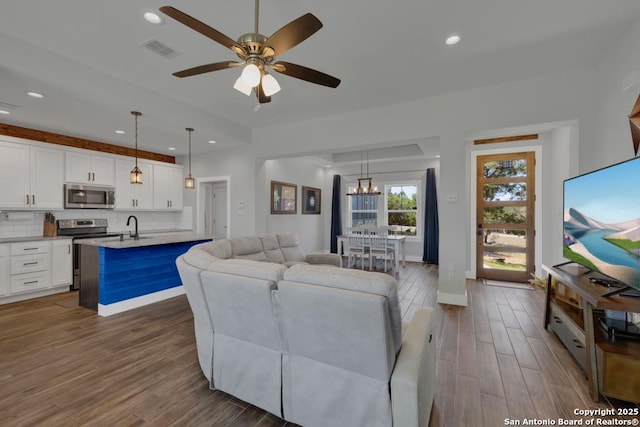 living room with dark wood-style floors, visible vents, recessed lighting, and a ceiling fan