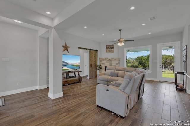 living room featuring a ceiling fan, visible vents, recessed lighting, dark wood-type flooring, and a barn door