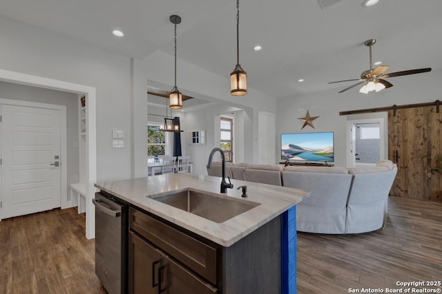 kitchen with a sink, dark wood-style flooring, a barn door, and stainless steel dishwasher