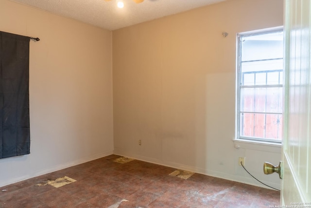 spare room with baseboards and a textured ceiling