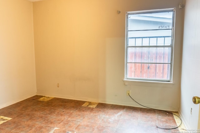 unfurnished room with baseboards