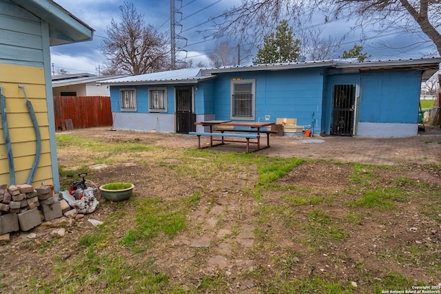 back of house featuring metal roof and fence