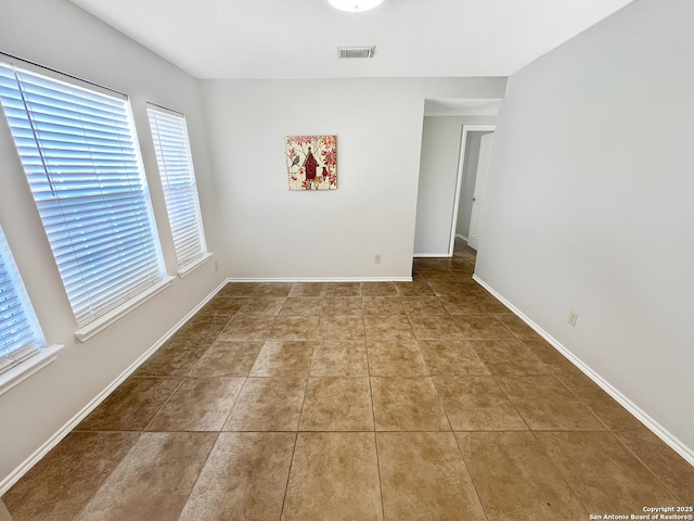 tiled empty room with baseboards and visible vents