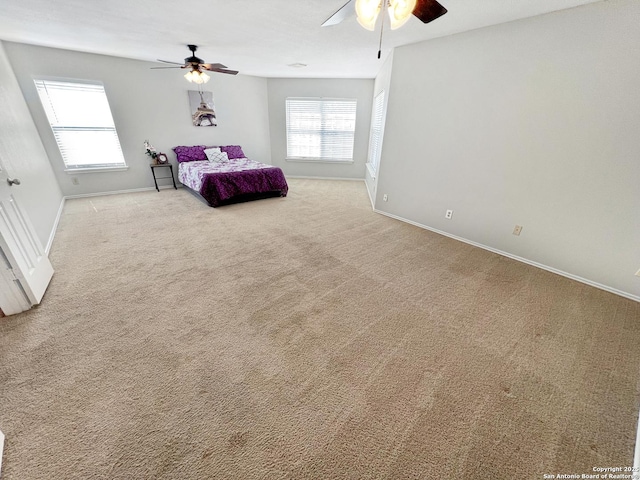 carpeted bedroom with baseboards, multiple windows, and ceiling fan