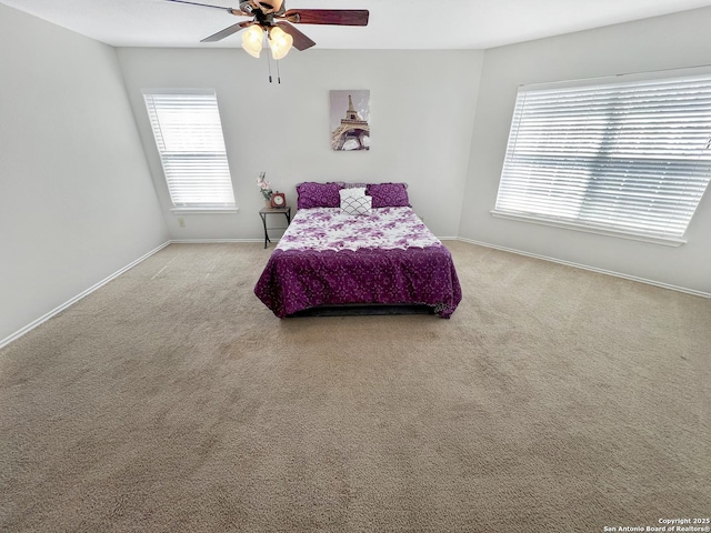 carpeted bedroom featuring baseboards, multiple windows, and ceiling fan