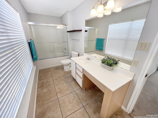 bathroom with tile patterned floors, combined bath / shower with glass door, toilet, and vanity