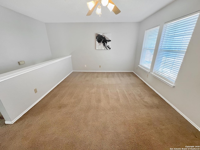 carpeted empty room featuring baseboards and ceiling fan