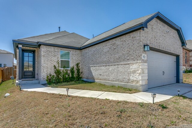 exterior space featuring fence, concrete driveway, a garage, a lawn, and brick siding