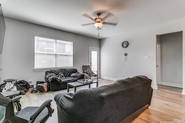 living room featuring baseboards, light wood finished floors, and ceiling fan