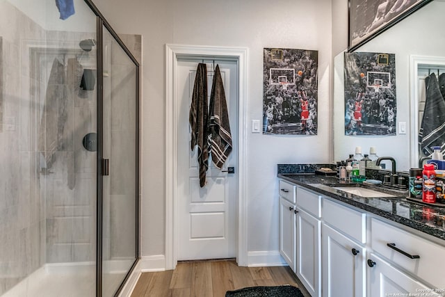 full bathroom with a stall shower, vanity, baseboards, and wood finished floors