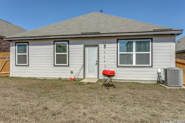 back of property featuring central air condition unit, a yard, and fence