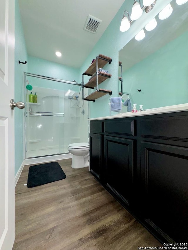 full bath featuring visible vents, toilet, wood finished floors, a shower stall, and vanity