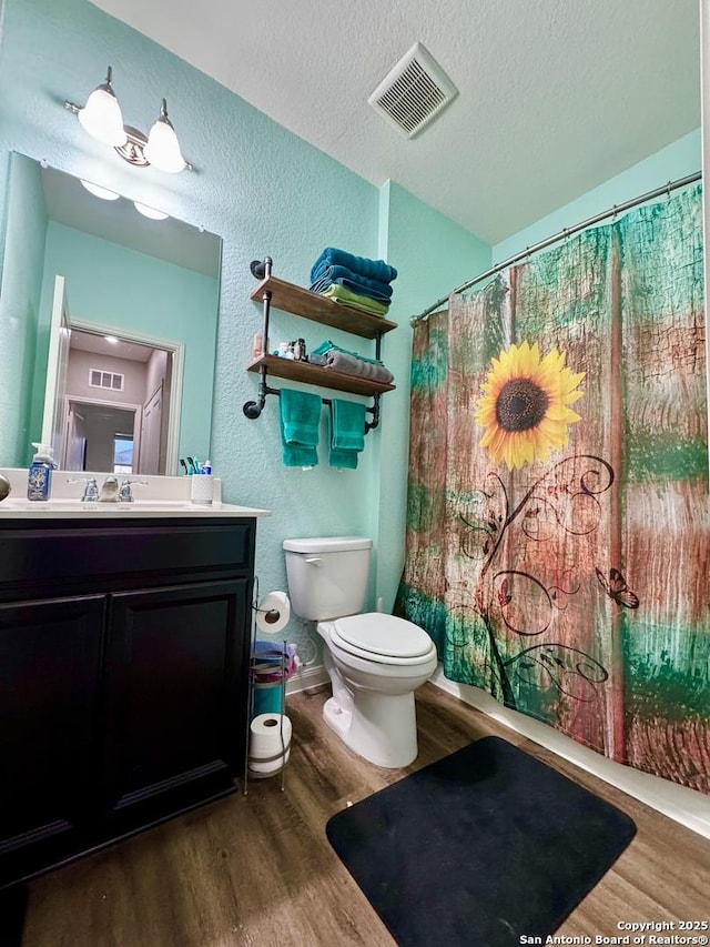 bathroom with visible vents, a textured ceiling, toilet, and wood finished floors