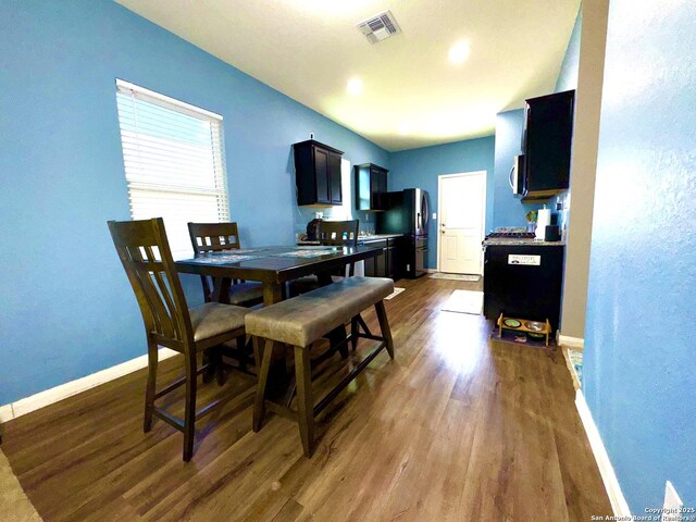 dining space with dark wood-type flooring, baseboards, and visible vents