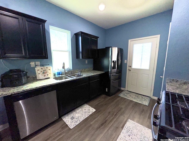 kitchen featuring a sink, plenty of natural light, dark cabinetry, dark wood finished floors, and stainless steel appliances