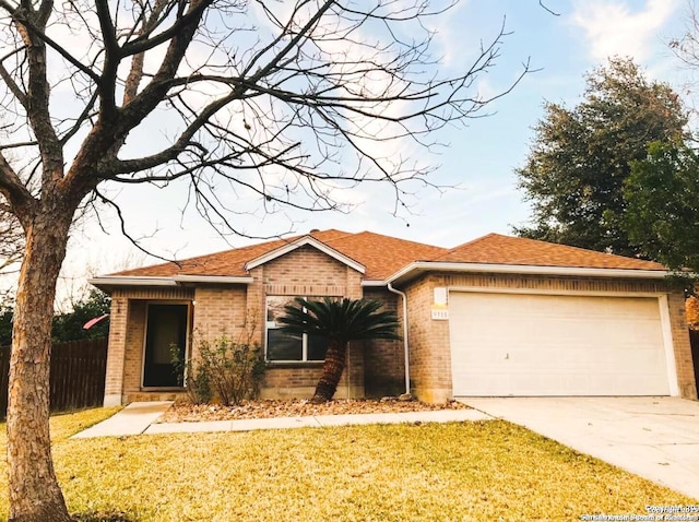 ranch-style home featuring brick siding, fence, concrete driveway, a front yard, and a garage