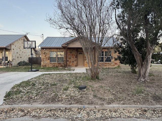 view of front of house featuring stone siding, metal roof, a standing seam roof, and fence