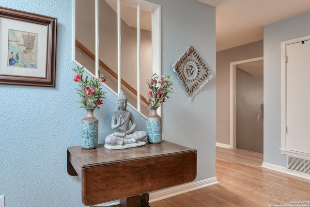 corridor featuring visible vents, stairs, baseboards, and wood finished floors