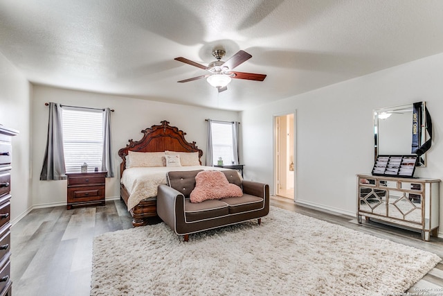 bedroom featuring a ceiling fan, wood finished floors, baseboards, and a textured ceiling