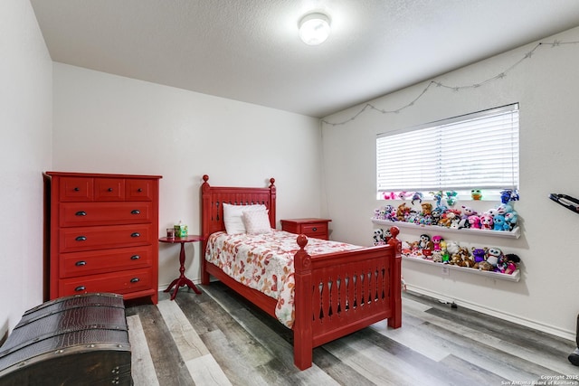 bedroom with a textured ceiling and wood finished floors