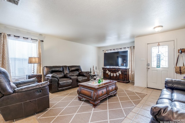 living room featuring a wealth of natural light, visible vents, a textured ceiling, and light tile patterned flooring