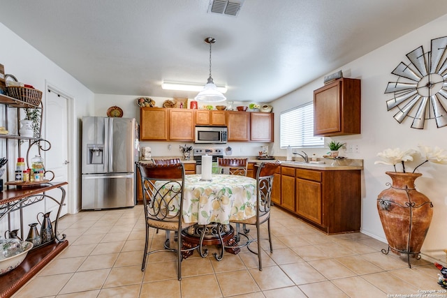 kitchen with brown cabinetry, visible vents, stainless steel appliances, and light tile patterned floors