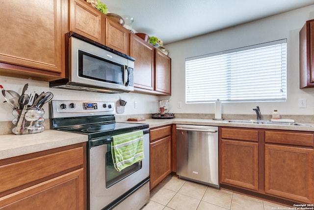 kitchen with light countertops, light tile patterned floors, appliances with stainless steel finishes, and a sink