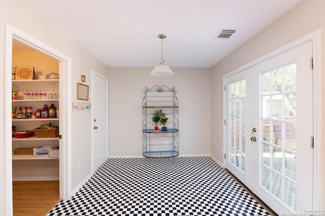 interior space with french doors, baseboards, a textured ceiling, and visible vents