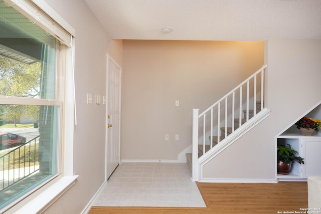 foyer entrance with stairs, baseboards, and light wood-type flooring