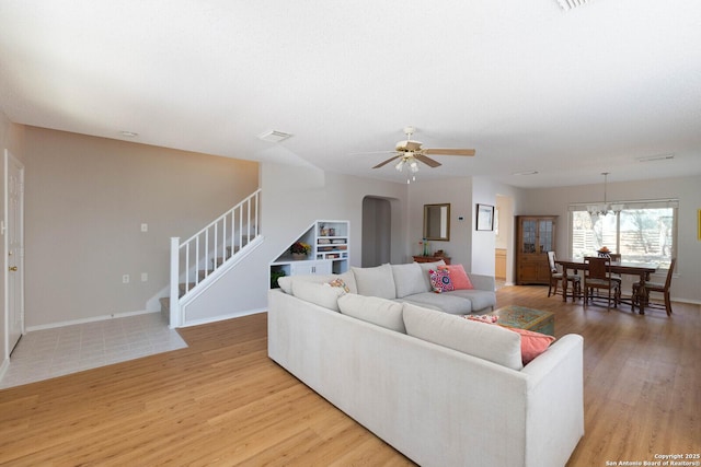 living room with ceiling fan, baseboards, light wood-style flooring, and stairs