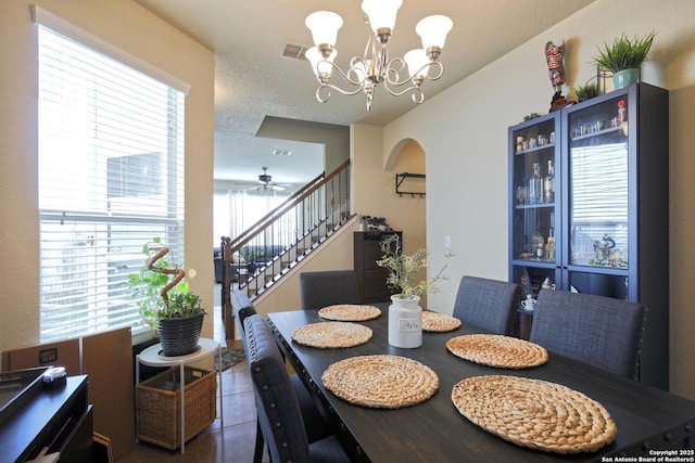 tiled dining space featuring visible vents, a textured ceiling, stairs, and an inviting chandelier