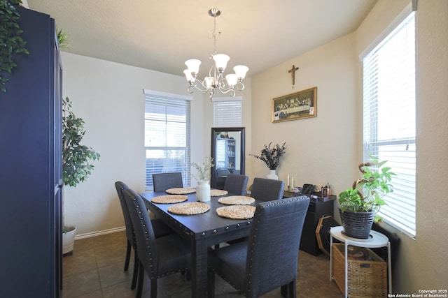 dining area with an inviting chandelier, dark tile patterned flooring, and baseboards