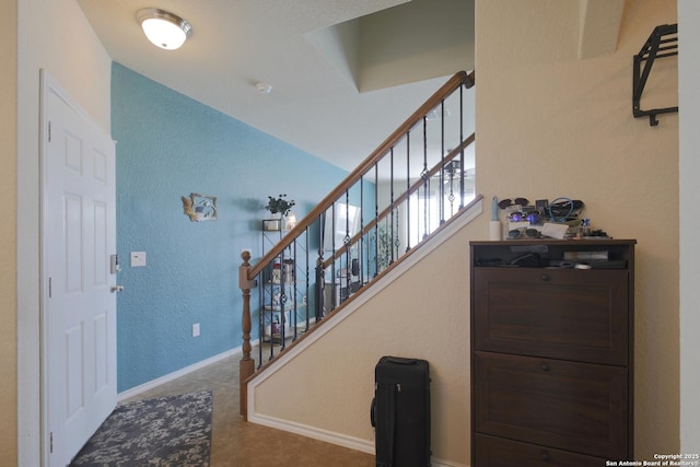 stairs featuring baseboards and a textured wall