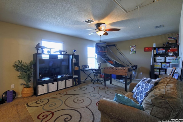 living area with visible vents, a ceiling fan, a textured ceiling, carpet floors, and attic access