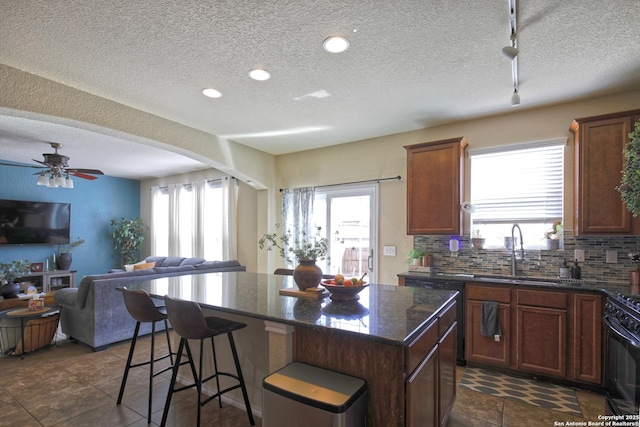 kitchen featuring a sink, backsplash, a kitchen island, open floor plan, and gas stove