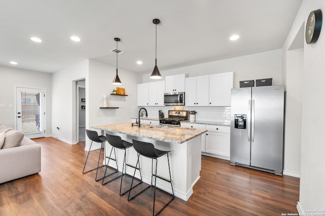 kitchen featuring a breakfast bar area, a sink, appliances with stainless steel finishes, white cabinetry, and tasteful backsplash