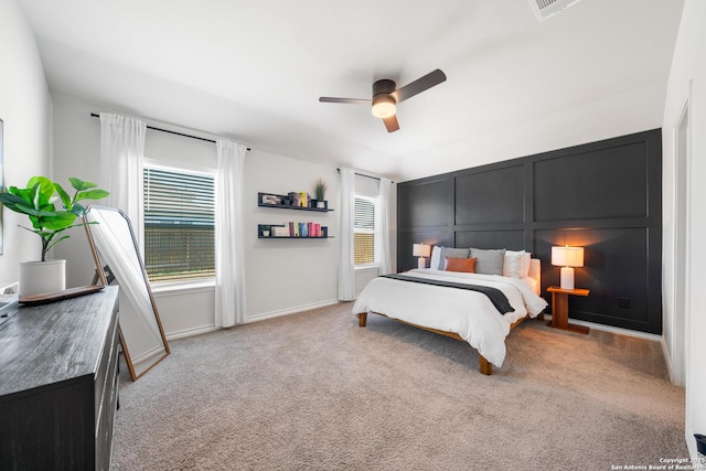 carpeted bedroom featuring a decorative wall and a ceiling fan