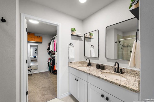 bathroom featuring a sink, a walk in closet, double vanity, and a shower stall