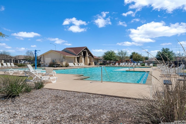 community pool with a patio area and fence