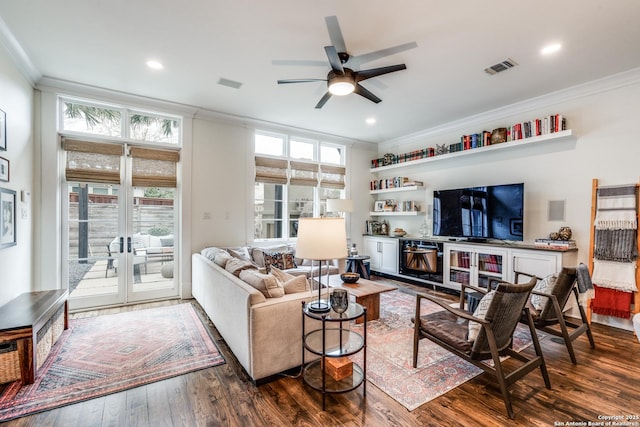 living room with ceiling fan, visible vents, ornamental molding, and dark wood finished floors