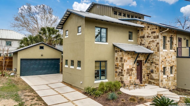 view of front of house featuring driveway, stucco siding, a garage, stone siding, and metal roof