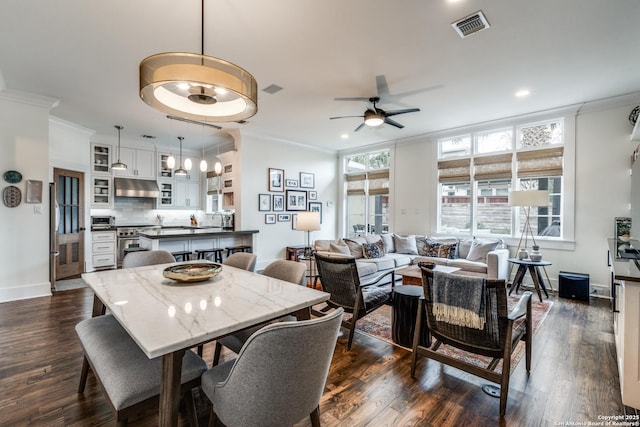 dining room with visible vents, dark wood-type flooring, a ceiling fan, and crown molding